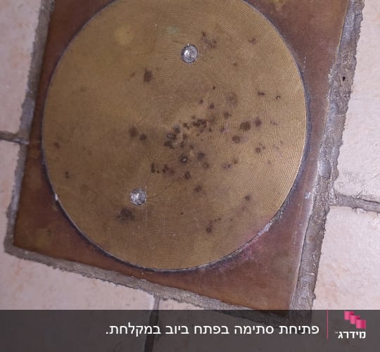 פתח ניקוז עגול ברצפה עם כתמים